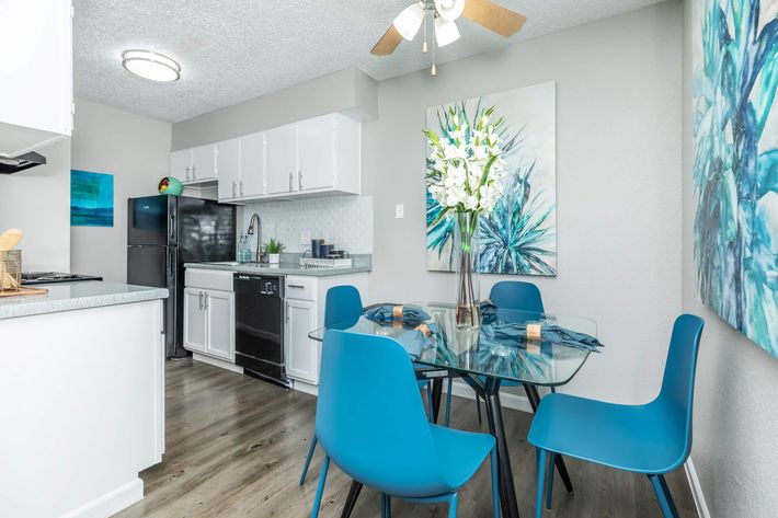 a kitchen with blue chairs and a white table at The Starburst Apartments