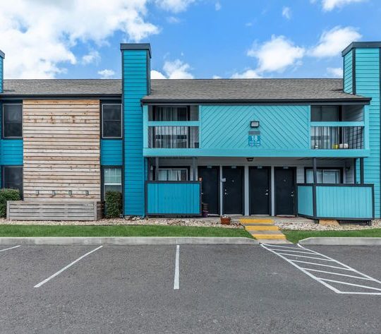 the exterior of an apartment building with blue siding at The Starburst Apartments