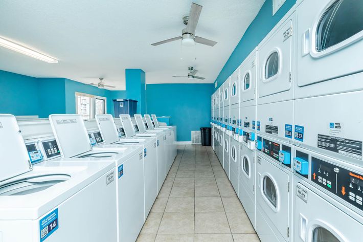 a laundry room with blue walls and white washers at The Starburst Apartments